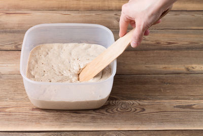 Close-up of hand holding bowl of wooden table