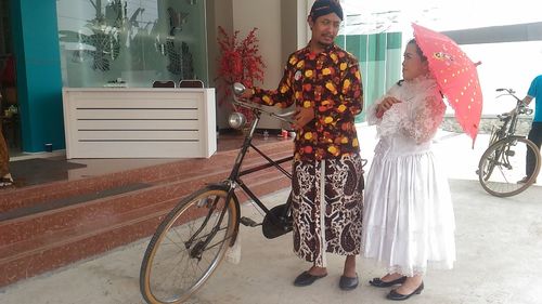 People standing by bicycle on street amidst plants