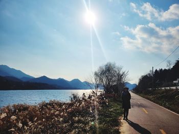 Rear view of woman standing on lake against sky