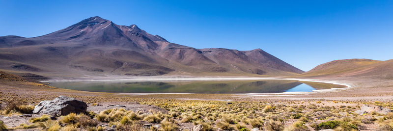 Scenic view of arid landscape against clear blue sky