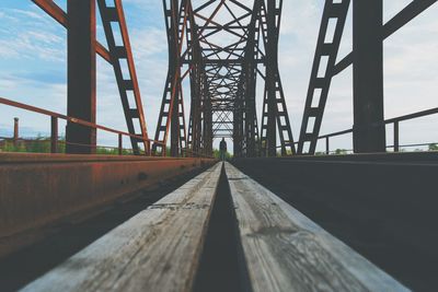 Surface level of man standing on bridge against sky
