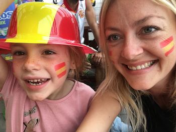 Smiling mother and daughter with painted face at stadium