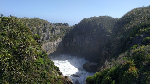 Scenic view of waterfall in forest against clear sky