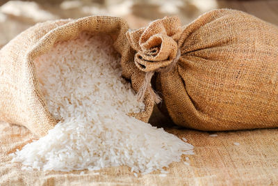 Close-up of rice spilling from sack on table