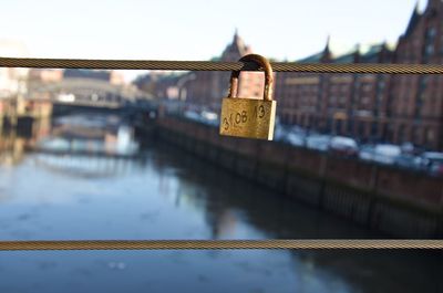 Close-up of lock on bridge over river against sky