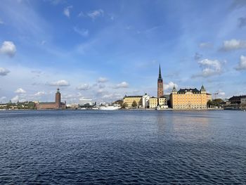 View of buildings by river against sky in city