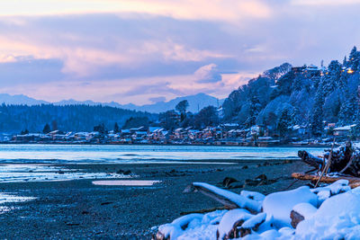 Scenic view of frozen lake by mountains against sky during sunset