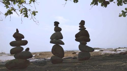 Stack of stones on beach against sky