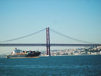 Suspension bridge over sea against clear sky