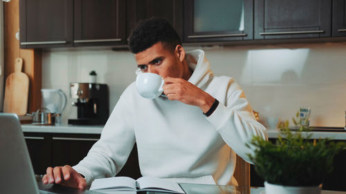 Young woman drinking coffee while sitting at home