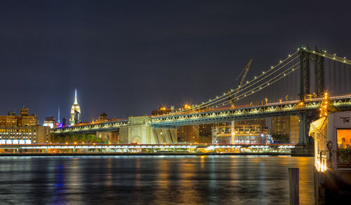 Illuminated bridge over river at night