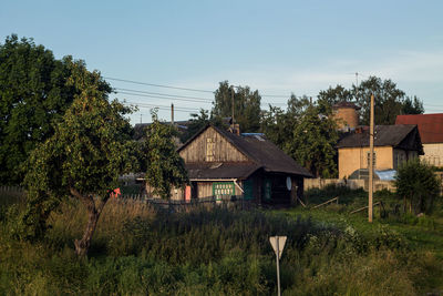 Houses and trees on field against sky