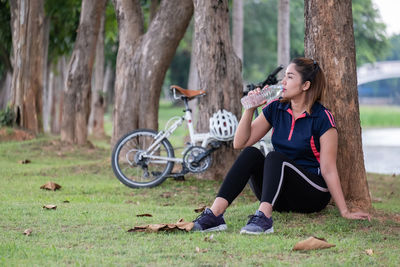 Young woman sitting on tree trunk in park