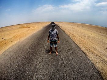 Full length of woman standing on road against sky