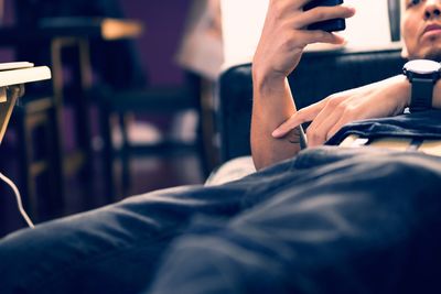 Midsection of man using mobile phone while sitting on table