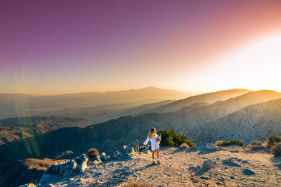 Woman with cat walking on mountain against sky