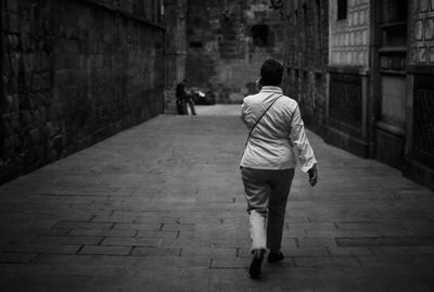 Rear view of man walking on footpath in city