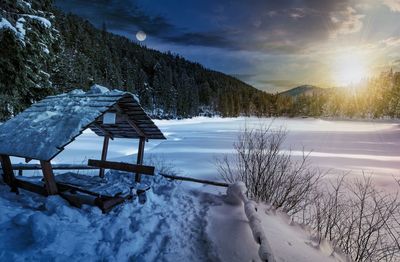 Snow covered land against sky during sunset