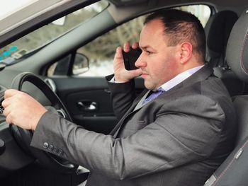 Businessman talking on mobile phone while sitting in car