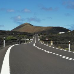 Empty road along landscape against sky