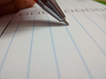 Cropped hand of person writing on book