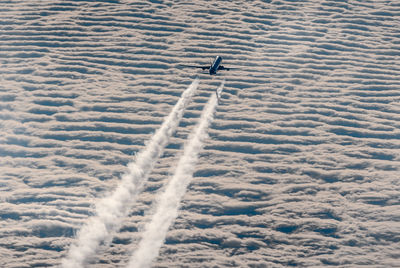 Aerial view of airplane above closed layer of clouds