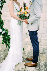 Midsection of bride holding bouquet