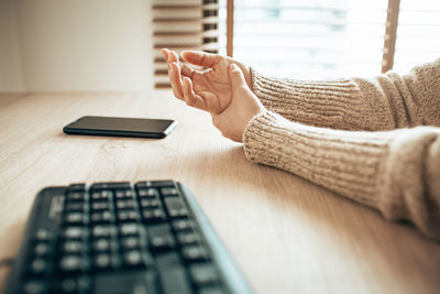 Cropped hands of woman by computer keyboard on table