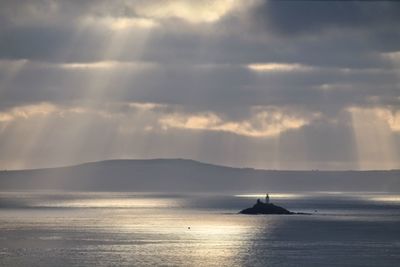 Boat sailing in sea against cloudy sky