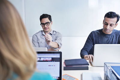 Serious business people using laptop computers during meeting at conference table