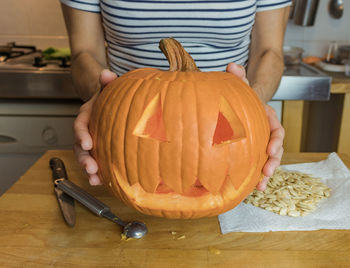 Midsection of man holding pumpkin on table