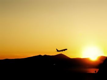 Silhouette of airplane flying against clear sky