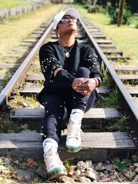 Full length of young man sitting on railroad track