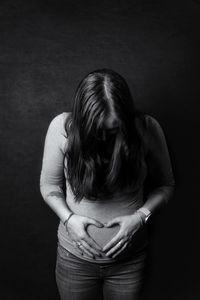 Midsection of woman standing against black background