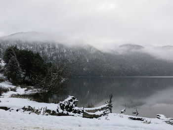 Scenic view of lake by snowcapped mountains against sky