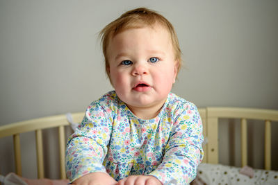 Cute girl of ten months old, playing alone in a crib at home in the afternoon or in the morning.