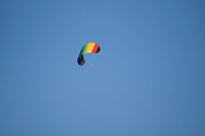 Low angle view of person paragliding against clear blue sky