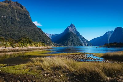 Scenic view of lake and mountains against clear blue sky