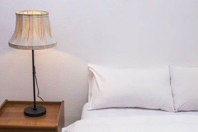 Electric lamp by bed against wall at home