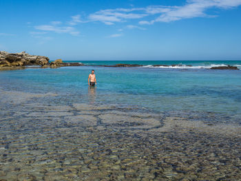 Man standing in sea against sky