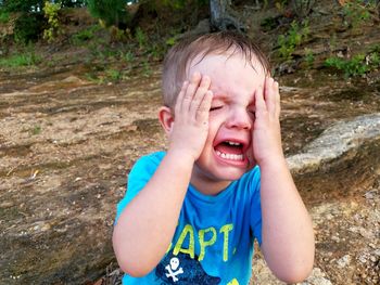 Close-up of crying boy on field at park