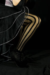 Low section of person wearing high heels against black background