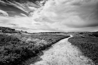 Road amidst field against sky