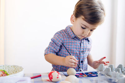 Cute boy painting easter egg at home