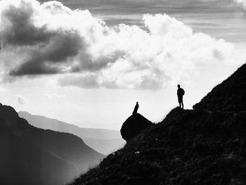 Man standing on mountain against cloudy sky