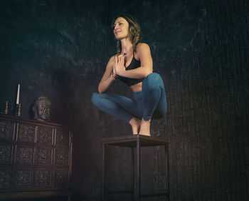 A charming girl in a sports uniform does yoga in an old room with a fireplace and candles