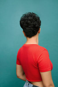 Young latina woman on her back with a red t-shirt , isolated vertical photo, tidewater green background
