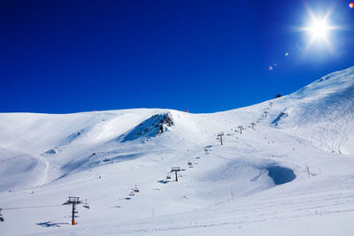 Scenic view of snow covered mountain against blue sky