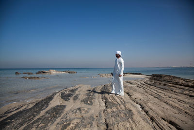 Woman standing on beach against clear sky