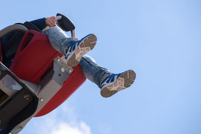 Low angle view of man sitting on amusement park ride against sky
